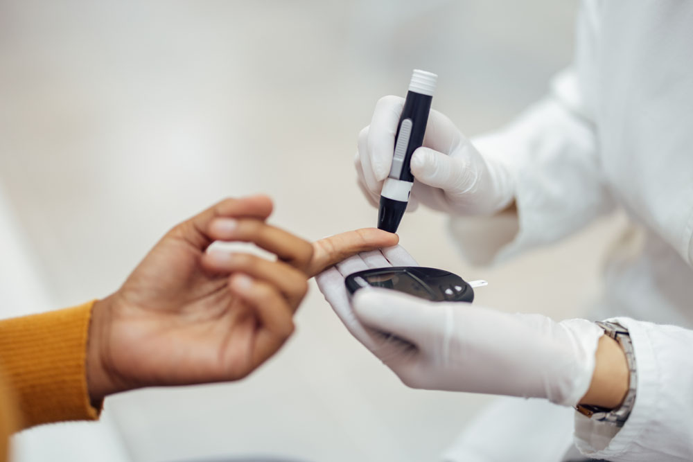 Healthcare worker using a lancing pen to check a patient’s blood glucose level.